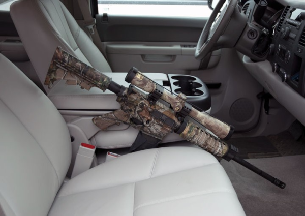 Camo rifle tucked between passenger's seat and center console of car