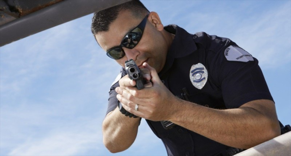 Police officer pointing gun in the direction of viewer