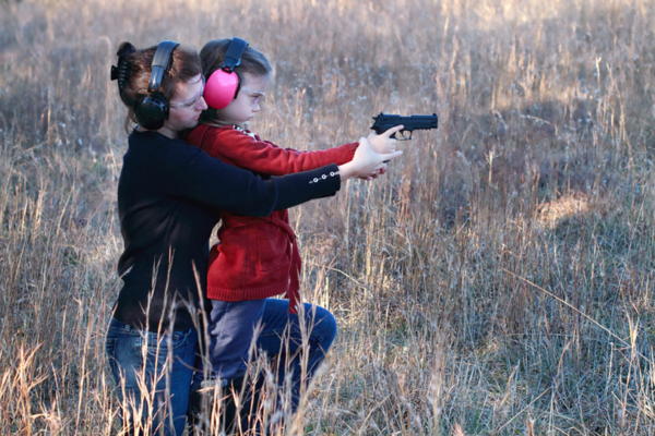 Women teaching girl to shoot pistol