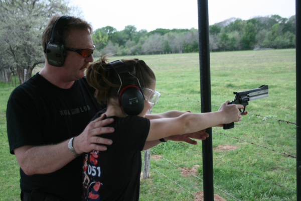 man teaching girl to shoot revolver