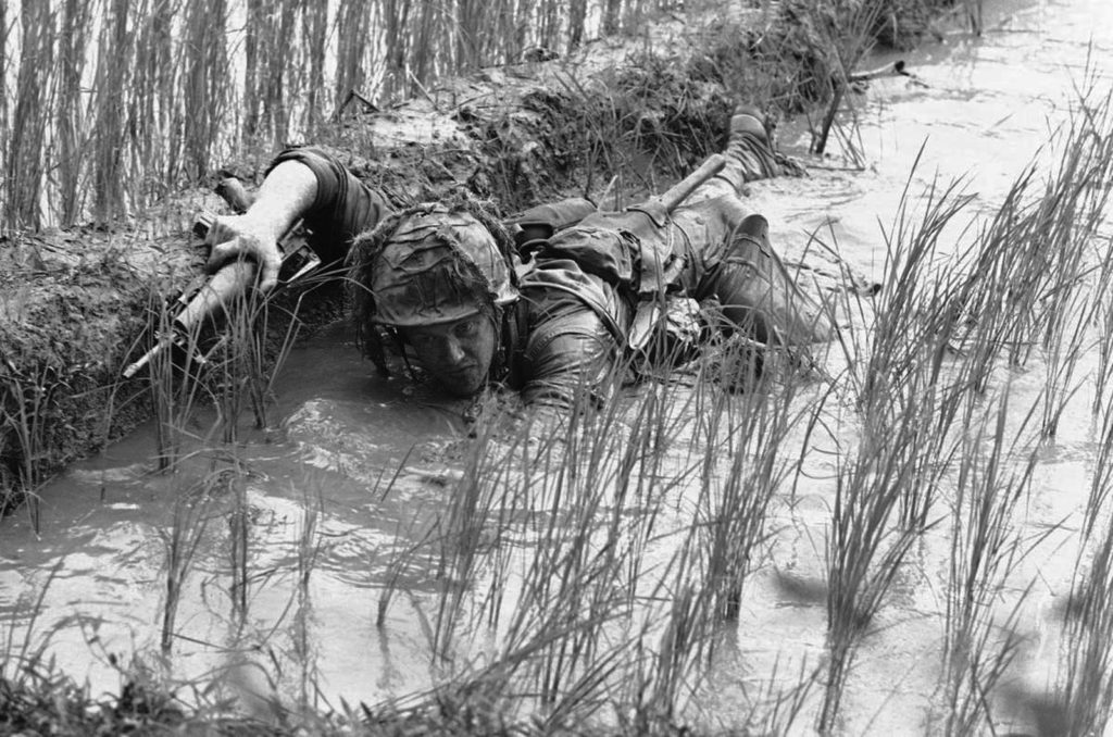 FILE - In this 1966 file photo, Pfc. Lacey Skinner of Birmingham, Ala., crawls through the mud of a rice paddy avoiding heavy Viet Cong fire near An Thi in South Vietnam, as troops of the U.S. 1st Cavalry Division fight a fierce 24-hour battle along the central coast. The war ended on April 30, 1975, with the fall of Saigon, now known as Ho Chi Minh City, to communist troops from the north. (AP Photo/Henri Huet, File)