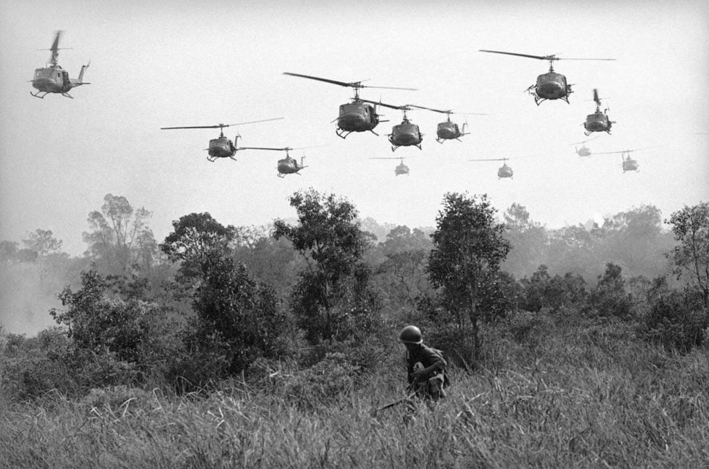 Hovering U.S. Army helicopters pour machine gun fire into tree line to cover the advance of Vietnamese ground troops in an attack on a Viet Cong camp 18 miles north of Tay Ninh on March 29, 1965, which is northwest of Saigon near the Cambodian border. Combined assault routed Viet Cong guerrilla force. (AP Photo/Horst Faas)