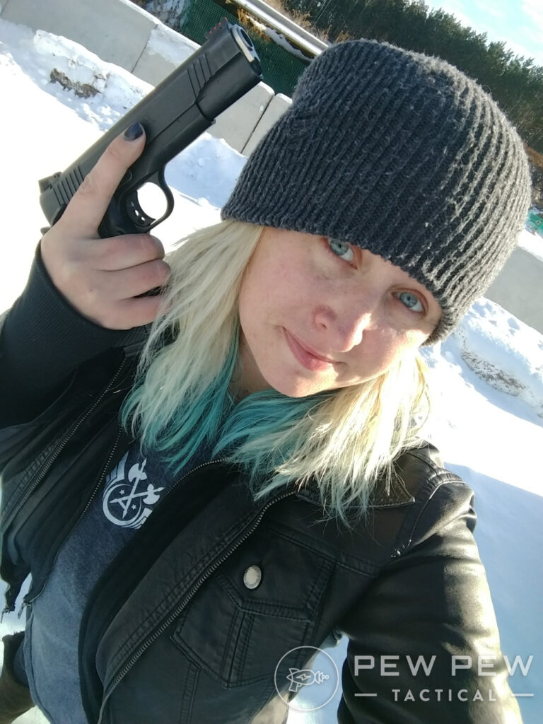 Kat in a beanie with a pistol