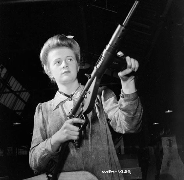 Woman worker poses with finished Sten submachinegun, Small Arms Plant, Long Branch, Ontario, Canada. May 1942 (Photo National Film Board of Canada)