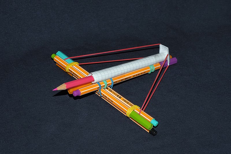 A small crossbow made out of pencils, rubber band and tape.