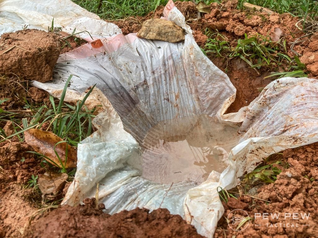 Hole dug in the ground lined with a plastic trash bag