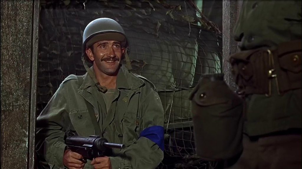 Tassos Bravos (Al Mancini) holds his Grease Gun at the hip